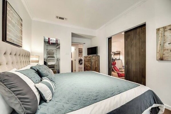 Una camera da letto con un letto grande, un armadio, una televisione e una porta che dà su un'altra stanza.
