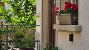Ein Gebäude mit Balkon, Topfpflanzen und einem Fenster mit roten Blumen.