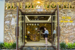The entrance of BLU BIZ HOTEL with a marble facade, a reception desk, and clocks on the wall. - Blubiz Hotel 5 (Hanoi)