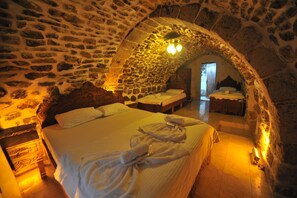 A stone-walled room with a bed, a bench, and a small table. - Artukhan Konak (Mardin)