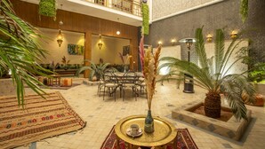 A spacious lobby with a high ceiling, a dining area, and a seating area with a coffee table and chairs. - Riad Azia: Serenity in Marrakech Your Oasis Awaits! 🌺 (Marrakech)