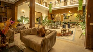 A spacious lobby with a high ceiling, a central seating area with a sofa and armchairs, a dining area with tables and chairs, and a balcony with a railing. - Riad Azia: Serenity in Marrakech Your Oasis Awaits! 🌺 (Marrakech)