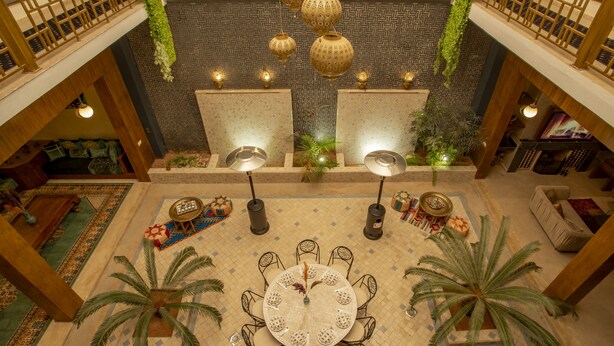 A spacious lobby with a central round table surrounded by chairs, a high ceiling with hanging lanterns, and a patterned floor. - Riad Azia: Serenity in Marrakech Your Oasis Awaits! 🌺 (Marrakech)