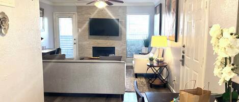 A modern living room with a fireplace, a television, and a ceiling fan.