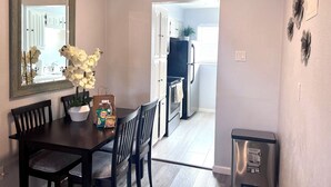 A dining area with a dark wooden table, two chairs, a vase with white flowers, and a mirror on the wall. - I20 - Gated 2BD Condo | Irving | DFW 10 Min | Pool (Irving)