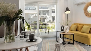 Un salon moderne avec un canapé blanc, une table ronde et un vase en verre contenant des fleurs.