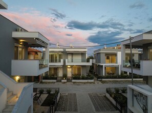 A modern residential complex with multiple two-story buildings, balconies, and a paved courtyard. - Roxani Residential Complex (Pangaio)