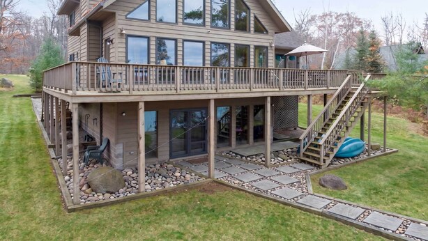 A two-story house with a balcony, large windows, and a stone pathway. - Twin Pines: Dog-Friendly Lakefront Cabin w/ Private Dock & Kayaks (Stone Lake)