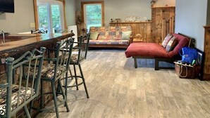 Une pièce spacieuse avec un bar en bois, un canapé confortable et un coin repas avec des chaises en métal.
