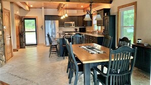 Une cuisine spacieuse dotée d’un grand îlot central, d’appareils électroménagers modernes et d’un coin repas avec une table et des chaises en bois.