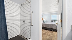 Et badeværelse med hvide metrofliser, en bruseniche med glasdør og et synligt håndklædetørrestativ.
