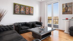 Una sala de estar moderna con una mesa de centro de vidrio, sofás de cuero negro y cuadros abstractos en las paredes.