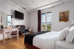 A bedroom with a large bed, a desk, a chair, a TV, and a painting. - Acropolis Elegant Penthouse (Athens)