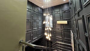 Un interior moderno con una lámpara central, paneles oscuros y una escalera de metal.