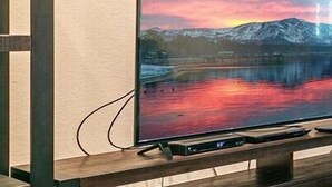 A flat-screen TV mounted on a wooden stand against a wall with two framed paintings above it. - Near golf course with summer pool (GR14) (Incline Village)