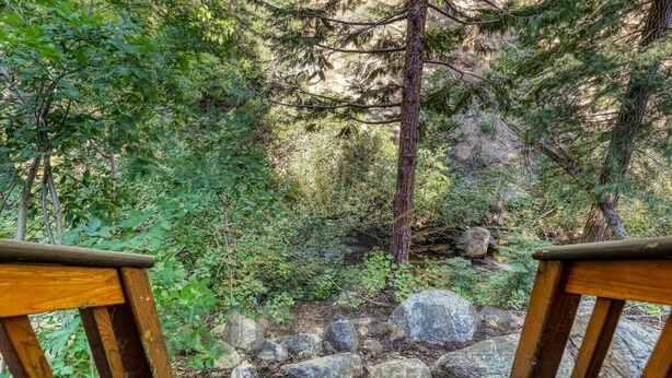 A wooden deck overlooking a forested area with a rocky stream. - Near golf course with summer pool (GR14) (Incline Village)