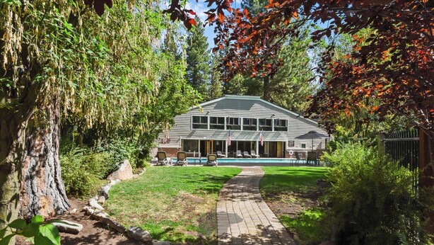 A two-story house with a swimming pool, surrounded by trees and a paved pathway. - Cozy three-bedroom condo w summer pool (FP1-15) (Incline Village)