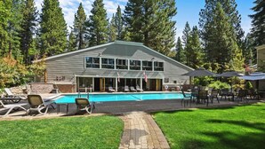 A two-story building with a swimming pool, outdoor seating, and a well-maintained lawn. - Cozy three-bedroom condo w summer pool (FP1-15) (Incline Village)