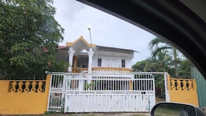 Une maison avec un portail blanc, des murs jaunes et un balcon.