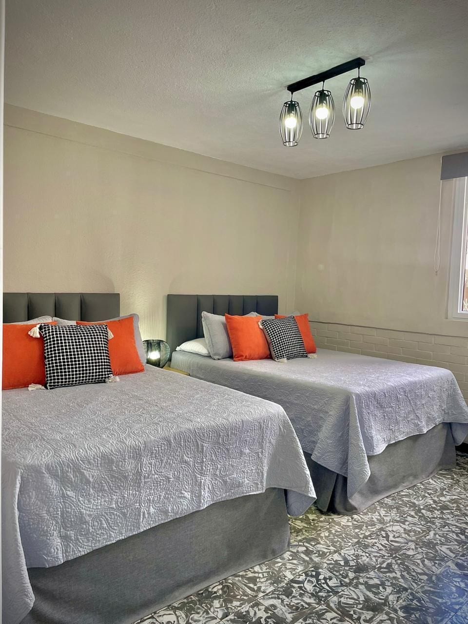 Habitación de hotel con dos camas, una ventana y una lámpara en el techo.