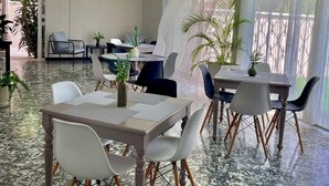 Uma área de refeições com mesas e cadeiras, piso ladrilhado e luminária no teto.