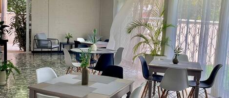 A dining area with tables and chairs, a tiled floor, and a ceiling light fixture.