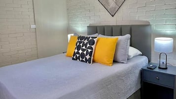 Habitación de hotel con cama, mesita de noche, lámpara de pared y un adorno mural.