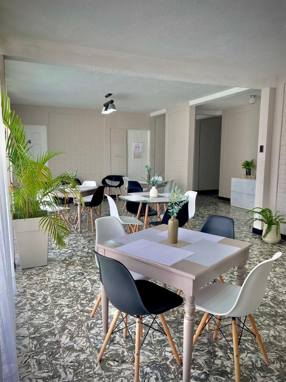 Un comedor con piso de mármol, paredes blancas y una combinación de muebles modernos y clásicos.