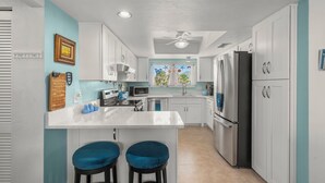 Una cocina moderna con armarios blancos, un refrigerador de acero inoxidable y una pared de acento azul.