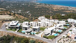 Un quartier résidentiel avec des maisons modernes, une piscine et une vue sur la mer.