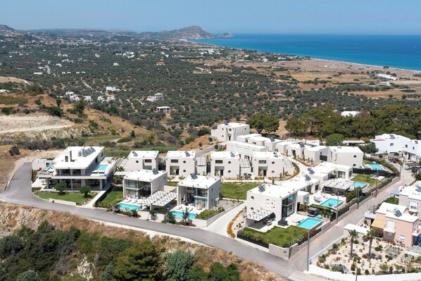 A residential area with modern houses, a swimming pool, and a view of the sea. - Trapezia Luxury Living - Opal (Afantou)