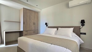 Une chambre à coucher comprenant un lit, une armoire, un bureau et un climatiseur fixé au mur.