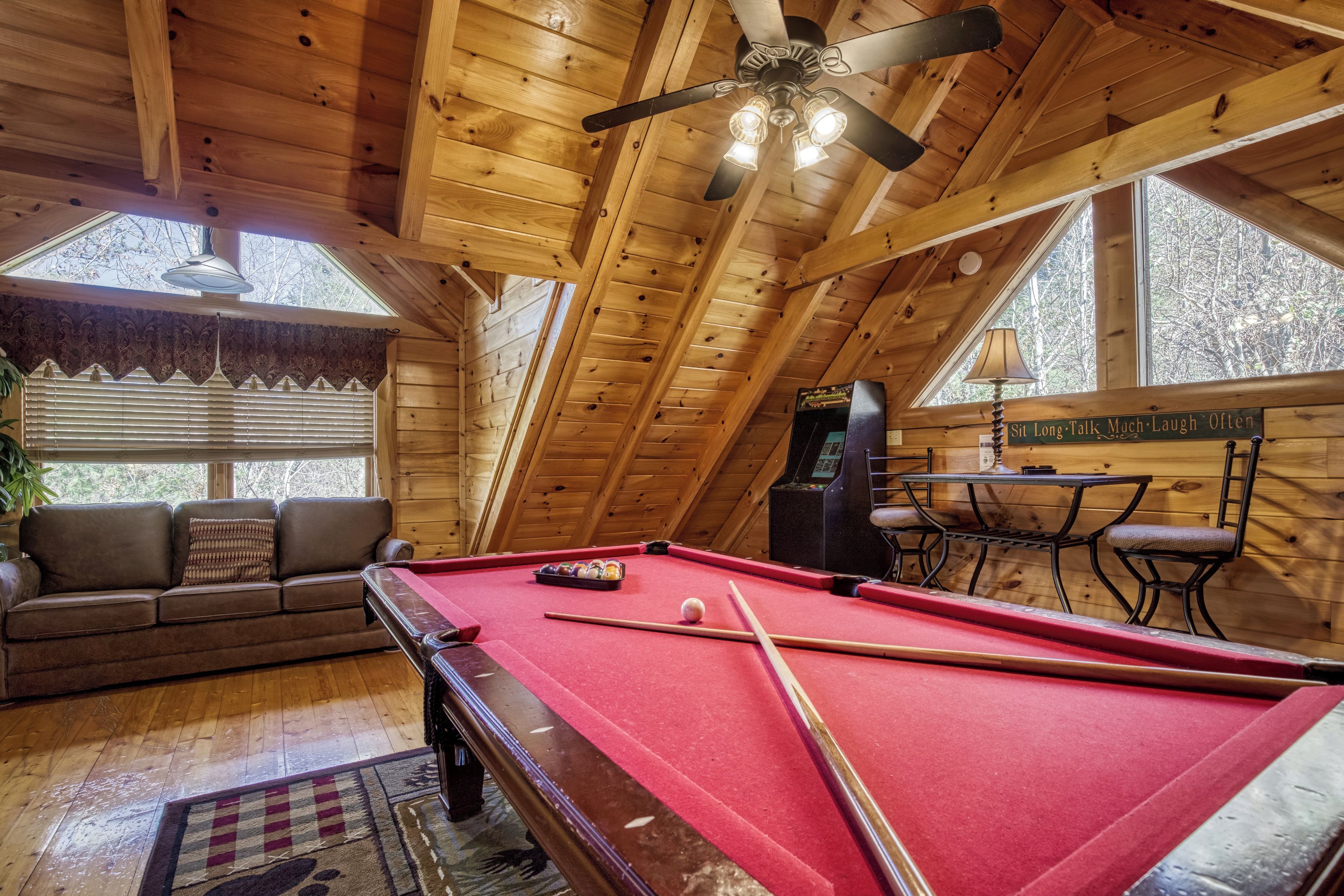 A cozy room with a pool table, a sofa, and a table with chairs.