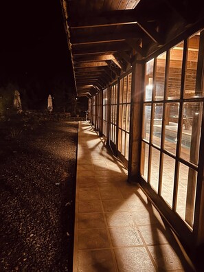 Un pasillo cubierto con amplias ventanas que conduce a un espacio al aire libre.