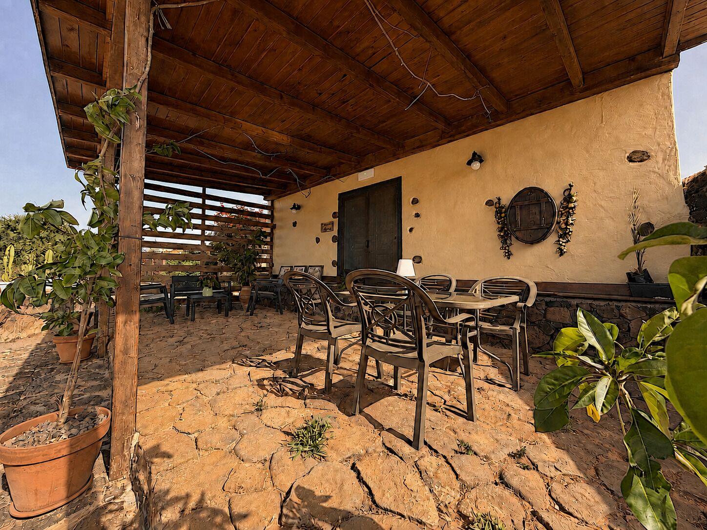 Eine Terrasse im Freien mit Holzmöbeln und Kübelpflanzen.