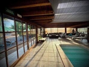 Un espacio interior amplio con piscina, ventanas grandes y zona de estar.