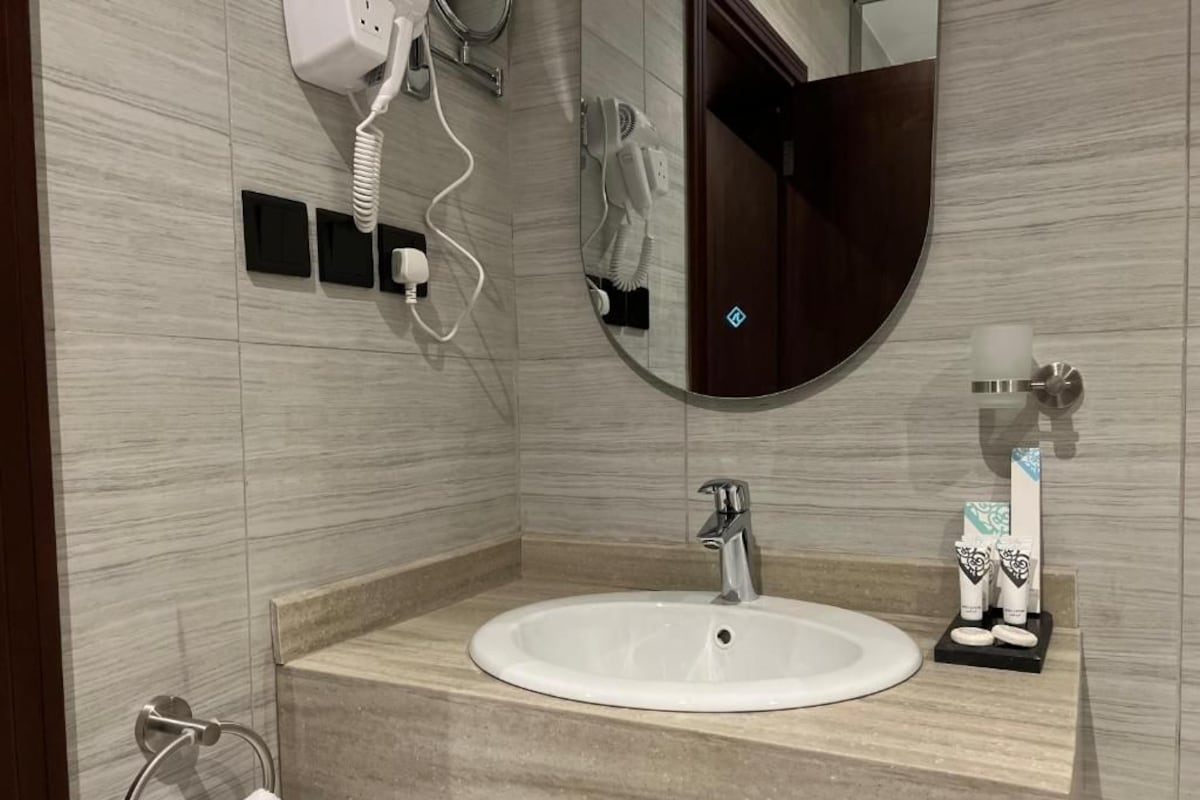 Une salle de bain moderne avec un miroir rond, un lavabo et un porte-serviettes.