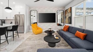 A modern living space with a kitchen, a dining area, and a seating area with a sofa and chairs.
