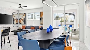 Ein modernes Wohnzimmer mit einem großen runden Tisch, blauen Stühlen, einer Couch und Kunstwerken an den Wänden.