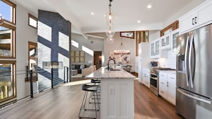 A modern kitchen with a central island, stainless steel appliances, and a chandelier.