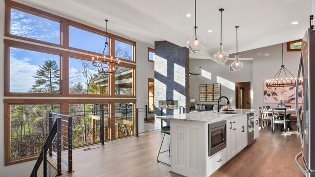 A spacious kitchen with large windows, a central island, and modern lighting fixtures.