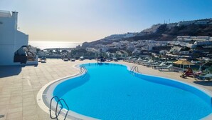A swimming pool with a view of the sea and a hillside town.