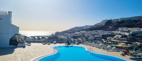 Una piscina con vista al mar y un pueblo en la ladera.