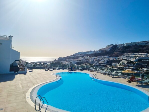 A swimming pool with a view of the sea and a hillside town.