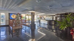 A spacious lobby with a polished black floor, a Christmas tree, and a reception desk.