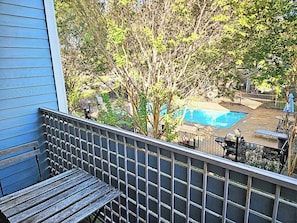 A residential backyard with a swimming pool, a wooden deck, and a metal fence.