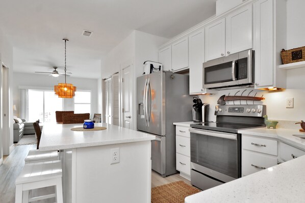 A modern kitchen with white cabinets, stainless steel appliances, and a central island. - "Dock, Relax, and Unwind at Waterside Retreat!" (Mexico Beach)