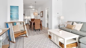 A modern living room with a sofa, coffee table, and a dining area with a table and chairs. - "Dock, Relax, and Unwind at Waterside Retreat!" (Mexico Beach)