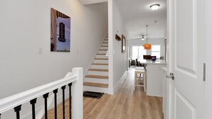 A modern interior with a staircase leading to a kitchen area. - "Dock, Relax, and Unwind at Waterside Retreat!" (Mexico Beach)