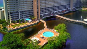 Un hotel moderno de gran altura con piscina rodeada de abundante vegetación.